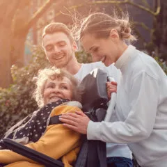 man and woman helping senior get into a car